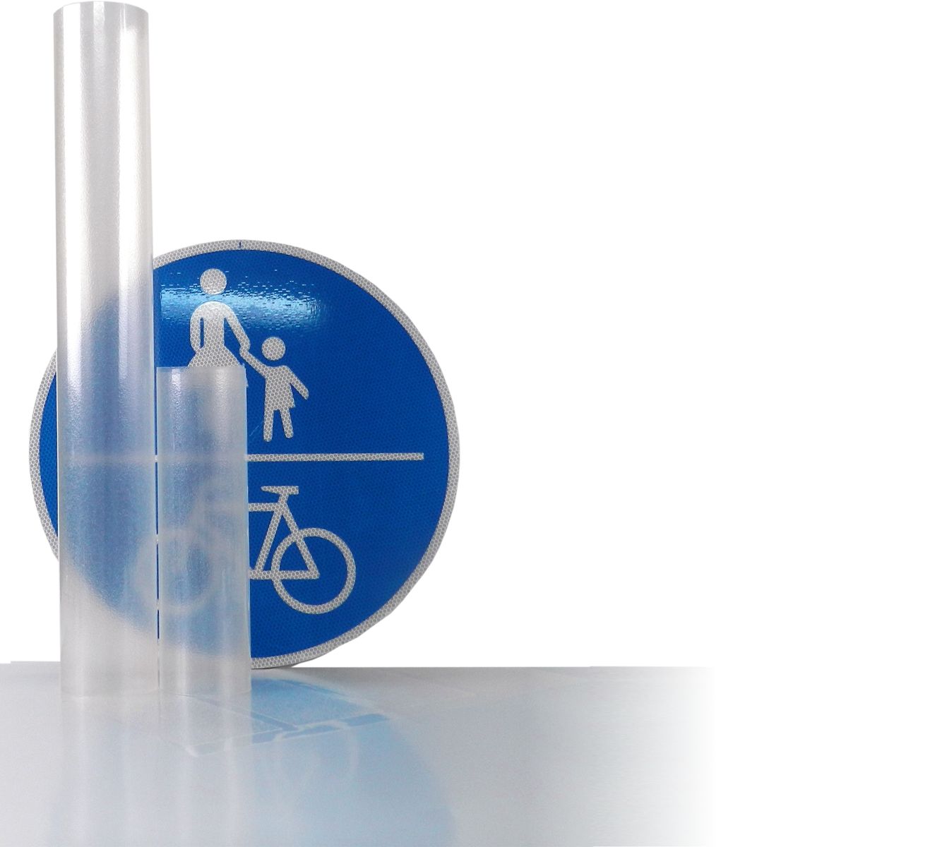 Ein kurzes und ein langes Stück aufgerollte transparente Antisticker Folie vor einem mit Astifol beklebtem Verkehrszeichen